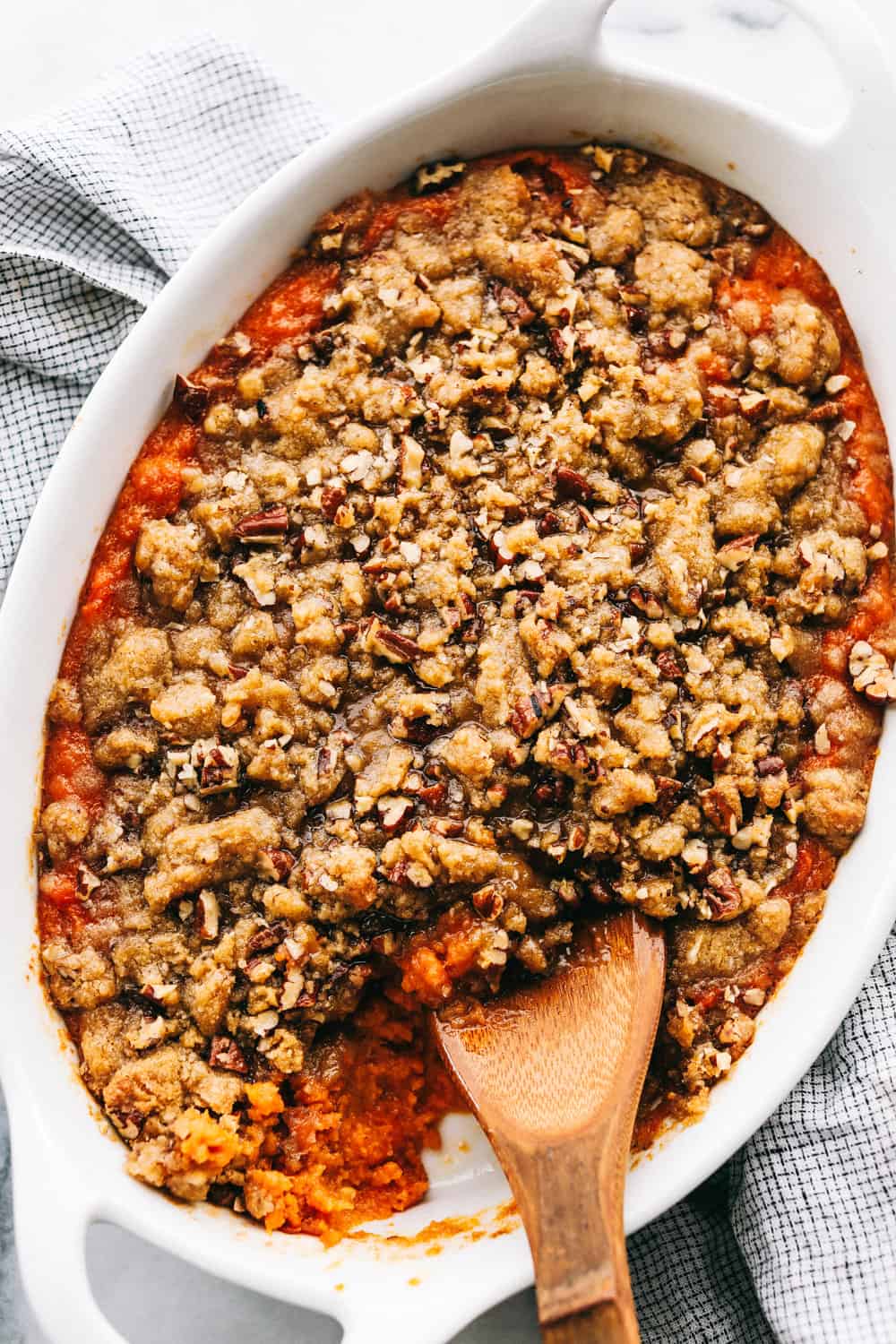 The best sweet potato casserole is smooth and creamy, sprinkled with a brown sugar pecan mixture. It's a sweet and savory side dish that is perfect for the holidays! A sweet potato casserole in a white serving dish.