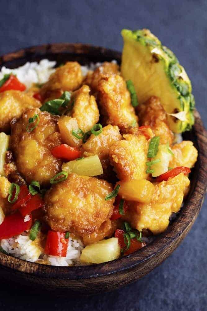 Delicious chicken that gets breaded and baked in a sweet and tangy pineapple sauce. It bakes to perfection and is so much better than takeout! baked sweet hawaiian chicken in a wooden bowl.