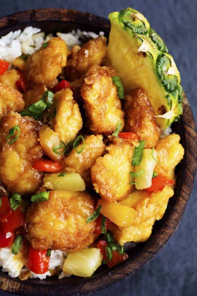 Delicious chicken that gets breaded and baked in a sweet and tangy pineapple sauce. It bakes to perfection and is so much better than takeout! Hawaiian chicken in a wooden bowl.