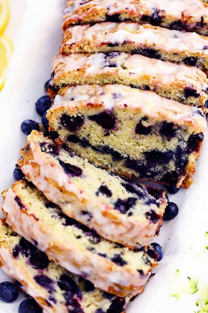 Blueberry Zucchini Bread with a Lemon Glaze will be one of the best quick breads you EVER make! Perfectly moist with two cups of zucchini hidden inside and bursting with fresh blueberries. The lemon glaze it the perfect finishing touch! Blueberry Zucchini Bread with a Lemon Glaze that has been sliced.