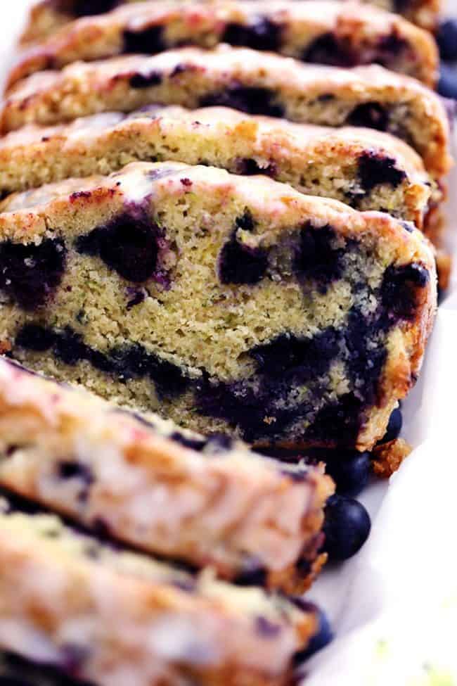 Blueberry Zucchini Bread with a Lemon Glaze will be one of the best quick breads you EVER make! Perfectly moist with two cups of zucchini hidden inside and bursting with fresh blueberries. The lemon glaze it the perfect finishing touch! Blueberry Zucchini Bread with a Lemon Glaze that has been sliced.