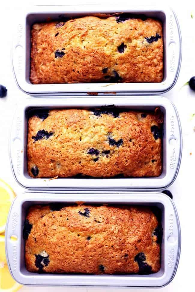 Blueberry Zucchini Bread with a Lemon Glaze will be one of the best quick breads you EVER make! Perfectly moist with two cups of zucchini hidden inside and bursting with fresh blueberries. The lemon glaze it the perfect finishing touch! Three loafs of Blueberry Zucchini Bread in the bread pan.