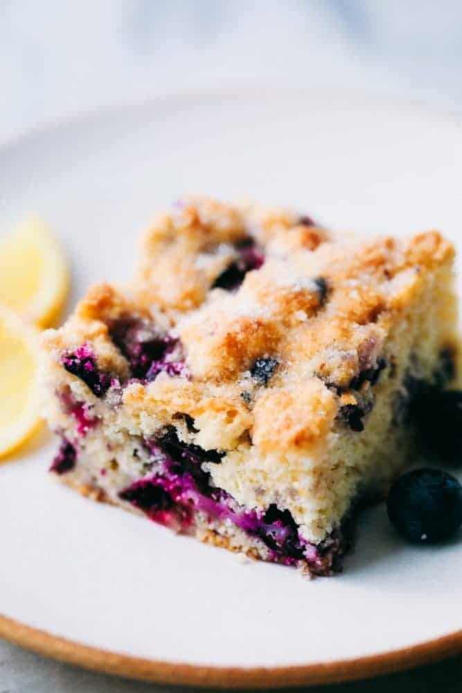 Blueberry buttermilk breakfast cake is so easy to throw together for breakfast. It is incredibly moist, buttery, and bursting with fresh blueberries inside. One piece is never enough! Close up of a slice of blueberry breakfast cake.