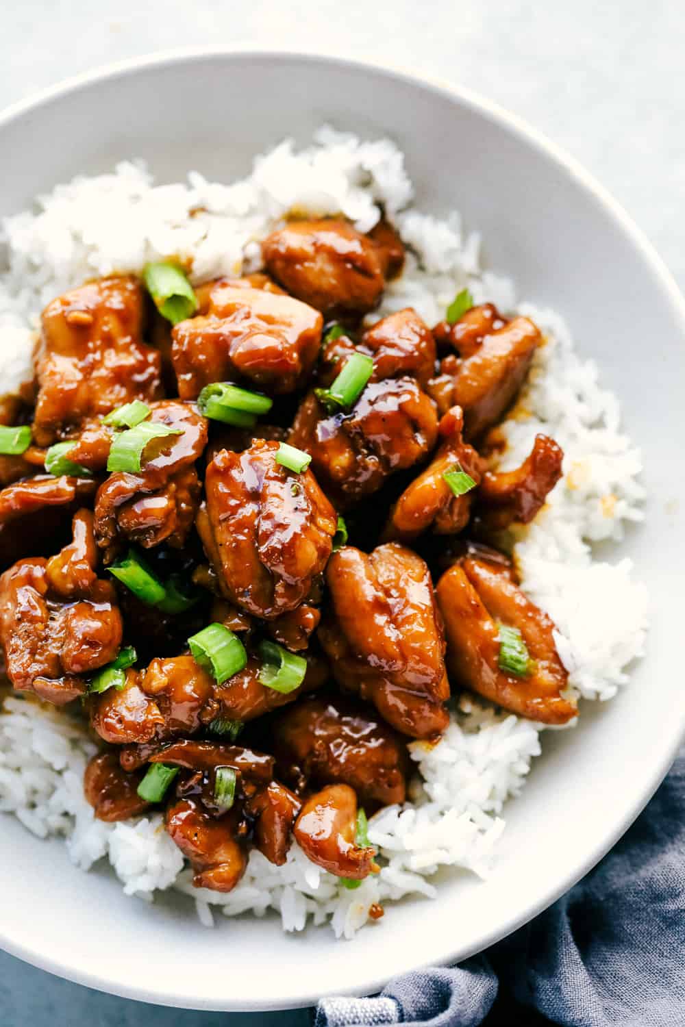 Best Bourbon Chicken is juicy, tender chicken thighs cut into pieces simmered in a sweet, brown sugar glaze that will melt in your mouth. Rich in flavor and served over rice for a complete meal! bourbon chicken over white rice and garnished with green onions