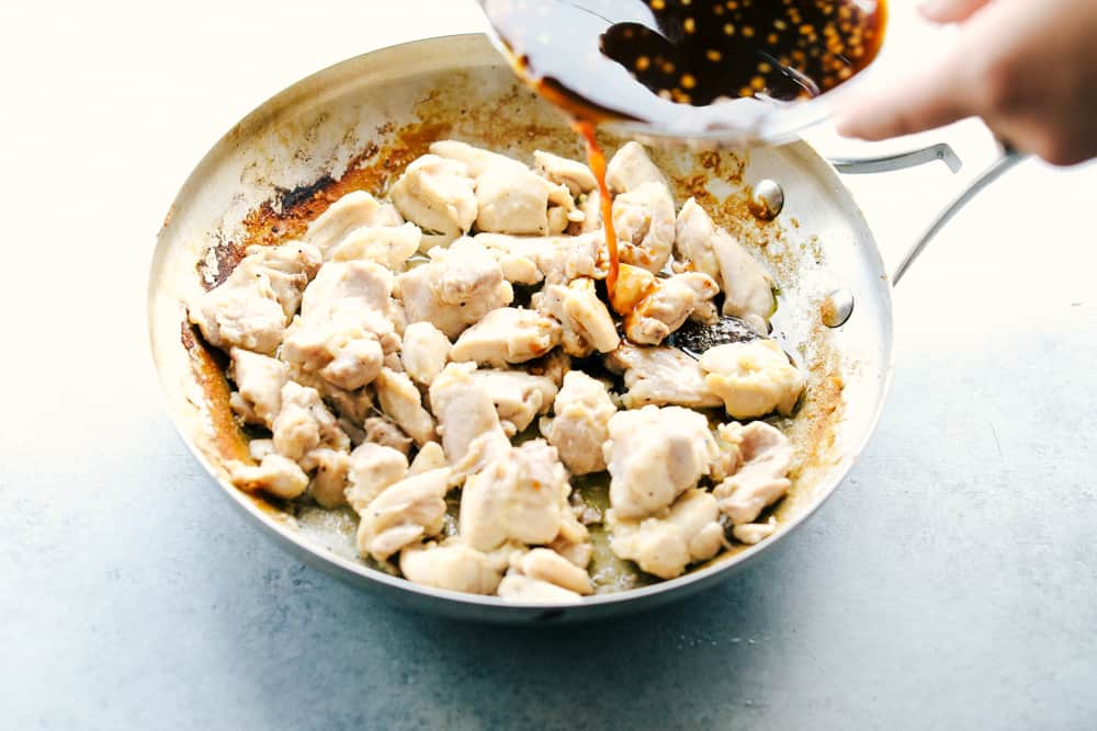 Best Bourbon Chicken is juicy, tender chicken thighs cut into pieces simmered in a sweet, brown sugar glaze that will melt in your mouth. Rich in flavor and served over rice for a complete meal! cooked chicken with glaze pouring over it