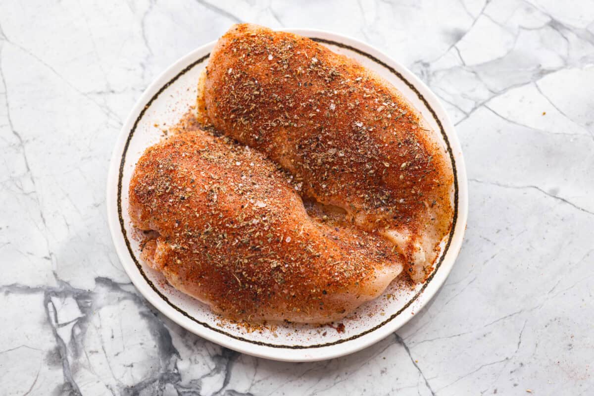 With this Air Fyer Chicken recipe, I am going to show you how to make the most insanely tender and juicy chicken! The secret? The incredible seasonings! They create a nice golden, crispy outside with a juicy, flavor-packed inside! Chicken breasts covered in oil and seasoning blend.