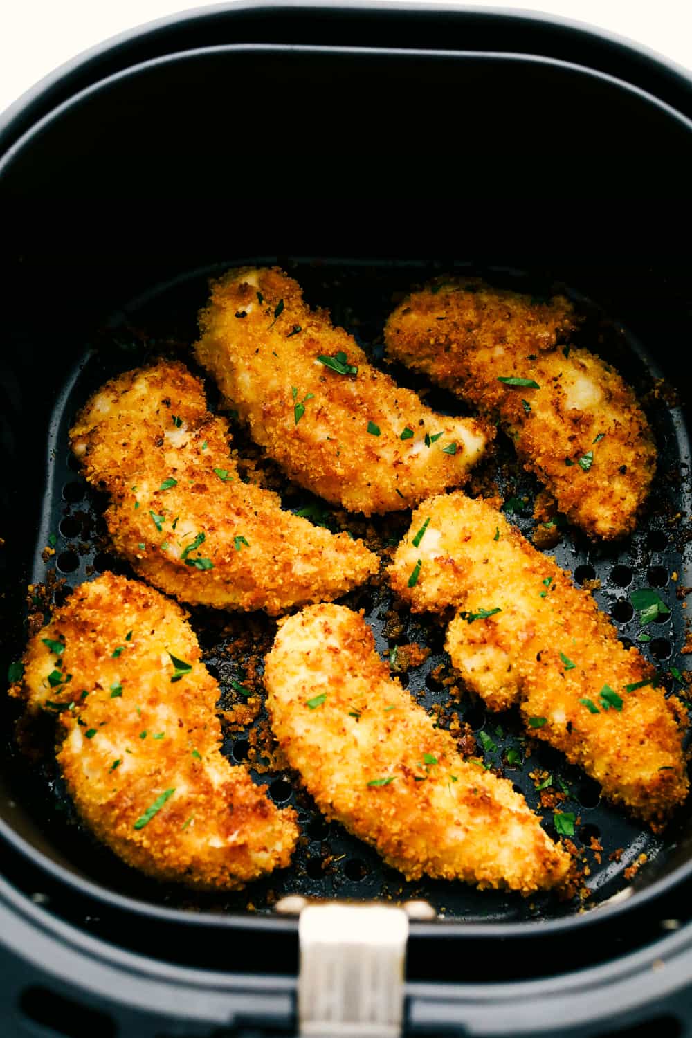 Breaded and cooked chicken in the air fryer basket. 