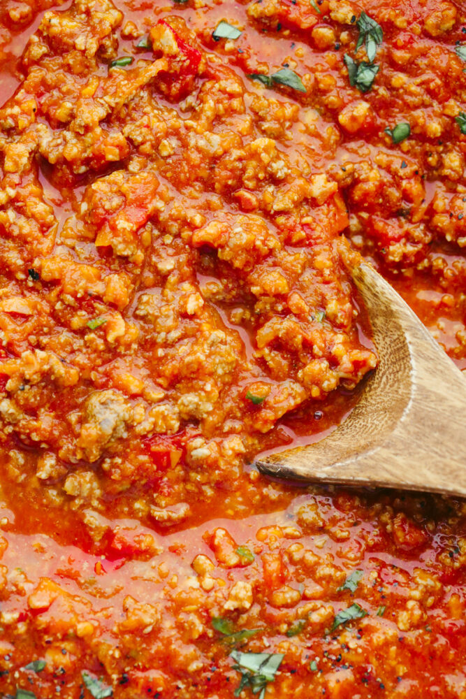 Zoomed in picture of the sauce with a wooden spoon in it. 