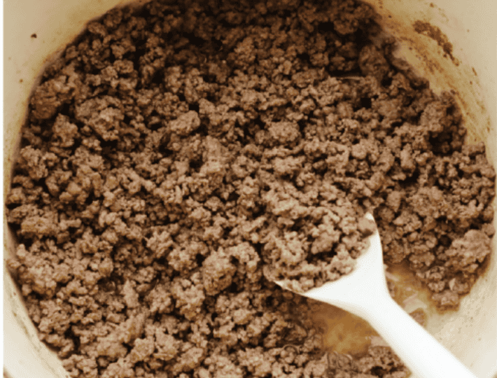 Ground beef being cooked in the bottom of the pot.