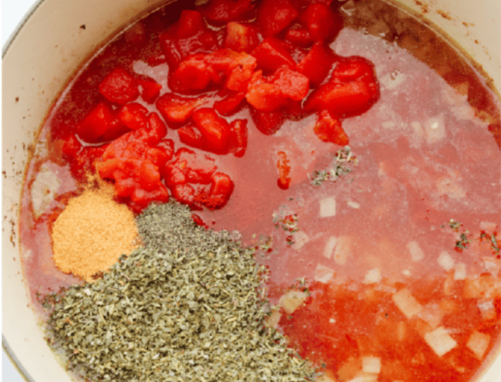 Tomatoes, water, and seasonings added to the pot with the onions.