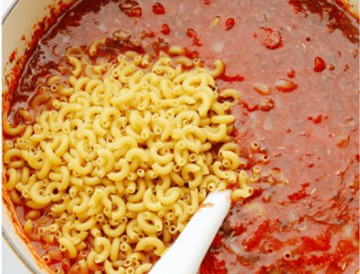 Macaroni noodles and beef added into the pot ready to simmer together. 